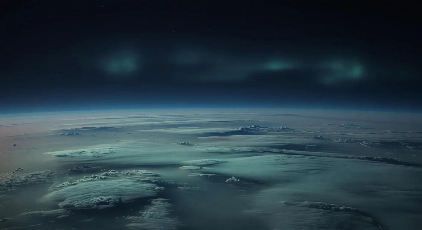 You seem to be hovering above an endless, darkened ocean of cloud, where subdued ridges, flattened domes, and scalloped banks of methane-hazed vapor stretch to a vast curved horizon under a nearly black-blue sky. There is no solid ground here—only layered atmospheric decks and deeper blue-black bands descending into the ice giant’s cold, high-pressure atmosphere, their pale cyan and muted turquoise tones softened by hydrocarbon haze and stratified mist. High above the high-latitude night side, a faint aurora appears not as bright curtains but as broad, patchy greenish-blue veils, blurred by the dense upper air and cast by the planet’s unusually tilted, offset magnetic field interacting with charged particles. In the dim, hushed light, with stars almost erased by the murk and shadows reduced to soft fissures in the cloud tops, the scene feels immense beyond intuition: a silent polar sky suspended over thousands of kilometers of slowly undulating atmosphere.